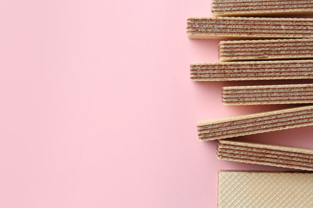 Tasty wafer sticks on pink background, flat lay with space for text. sweet food