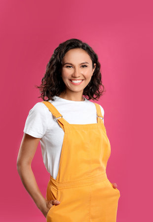 Happy young woman in casual outfit on pink backgroundの写真素材