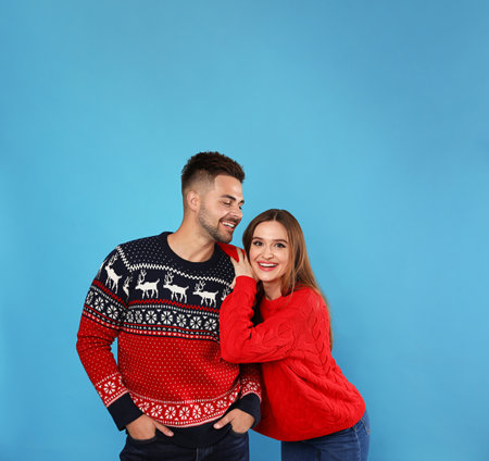 Couple wearing Christmas sweaters on blue backgroundの写真素材