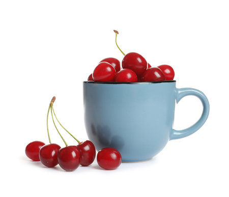 Light blue cup of delicious ripe sweet cherries on white backgroundの写真素材