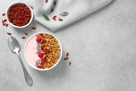 Smoothie bowl with goji berries and spoon on gray table, flat lay. Space for textの写真素材
