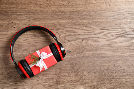 Modern headphones and gift box on wooden background, top view with space for text. christmas music conceptの写真素材