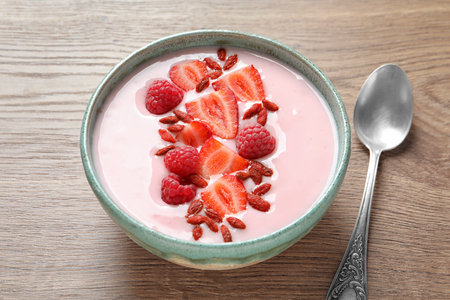 Smoothie bowl with goji berries and spoon on wooden tableの写真素材