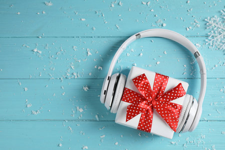 Modern headphones and gift box on blue wooden background, top view with space for text. christmas music conceptの写真素材