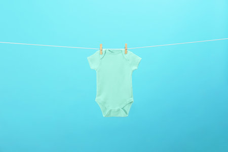 Baby bodysuit hanging on clothes line against blue background. laundry dayの写真素材