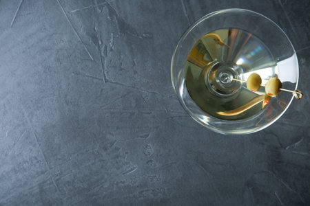 Glass of Classic Dry Martini with olives on dark gray table, top view. Space for textの写真素材