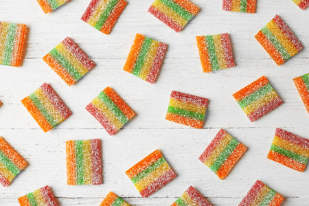 Tasty jelly candies on white wooden table, flat lay