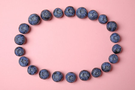 Frame of ripe blueberries on pink background, flat lay with space for textの写真素材