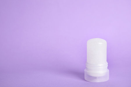 Natural crystal alum stick deodorant on lilac background. Space for textの写真素材