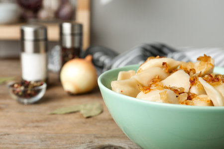 Delicious cooked dumplings with fried onion on wooden table, closeup. Space for textの写真素材