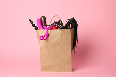 Paper shopping bag with different sex toys on pink backgroundの写真素材