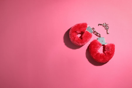 Red furry handcuffs and keys on pink background, flat lay with space for text. sex toyの写真素材