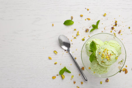 Delicious green ice cream served in dessert bowl on white wooden table, top view. Space for textの写真素材