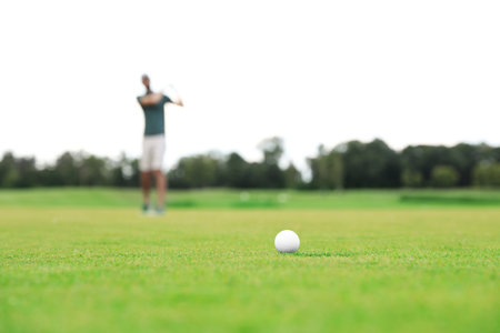 Man playing golf on green course, ball in focus. Sport and leisureの写真素材