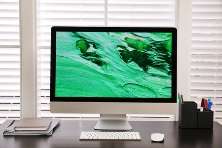 Comfortable workplace near window with white horizontal blinds in roomの写真素材