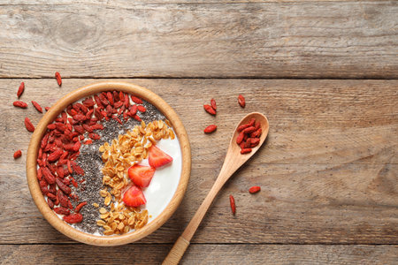 Smoothie bowl with goji berries and spoon on wooden table, flat lay. Space for textの写真素材