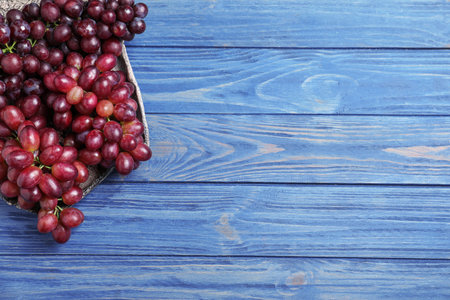 Fresh ripe juicy grapes on blue wooden table, top view. Space for textの写真素材