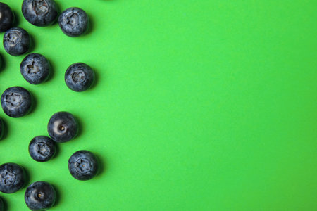 Tasty ripe blueberries on green background, flat lay with space for textの写真素材