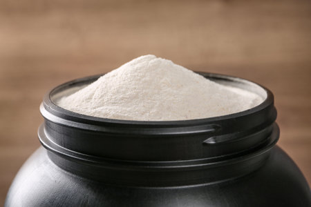 Black jar full of protein powder on brown background, closeup