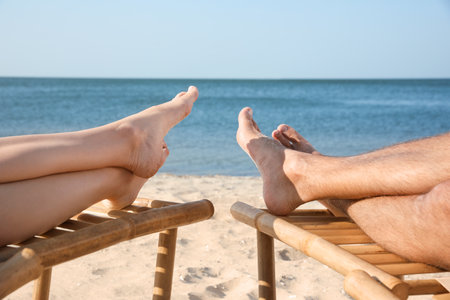 Young couple relaxing in deck chairs on beach near sea, closeupの写真素材