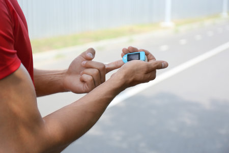 Young man checking pulse with medical device after training, closeup