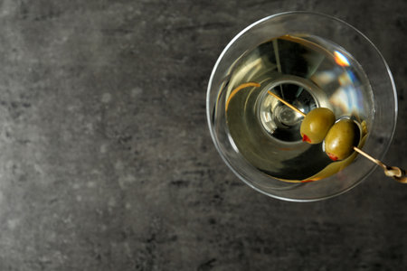 Glass of Classic Dry Martini with olives on grey table, top view. Space for textの写真素材