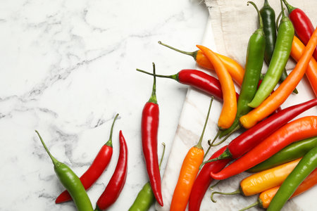 Different chili peppers on marble table, flat lay. Space for textの写真素材