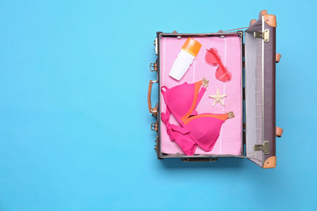 Open vintage suitcase with beach objects on blue background, top view. Space for textの写真素材
