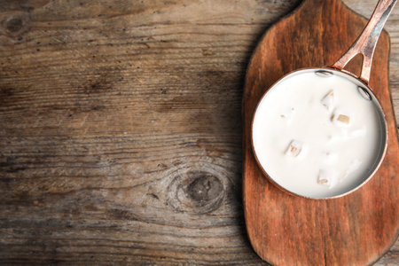 Delicious creamy sauce in pan on wooden table, top view. Space for textの写真素材