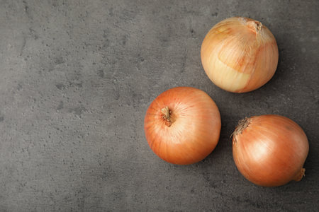 Ripe onions on grey table, flat lay with space for textの写真素材