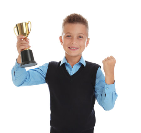 Happy boy in school uniform with golden winning cup isolated on whiteの写真素材