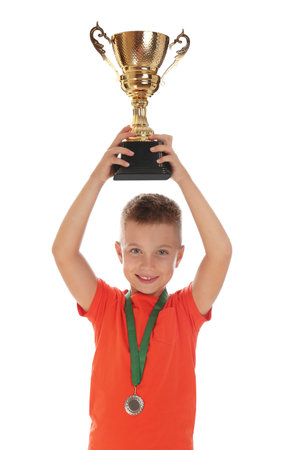 Happy boy with golden winning cup and medal isolated on whiteの写真素材