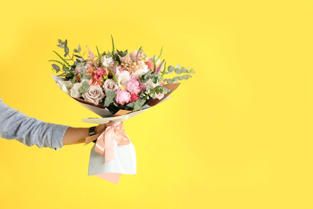 Man holding beautiful flower bouquet on yellow background, closeup view. Space for textの写真素材