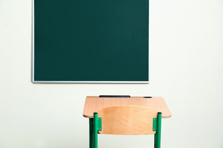 Modern empty school desk near chalkboard in classroomの写真素材