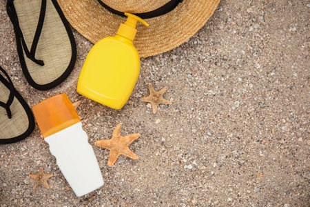 Flat lay composition with bottles of sun protection body cream on sand beach, space for textの写真素材