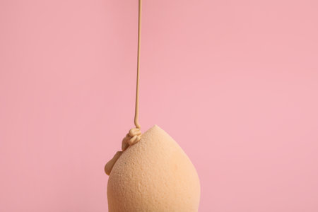 Liquid foundation pouring on makeup sponge against pink backgroundの写真素材