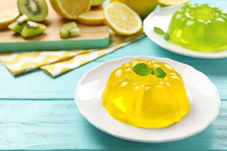 Plates of tasty fruit jelly on blue wooden table, space for textの写真素材