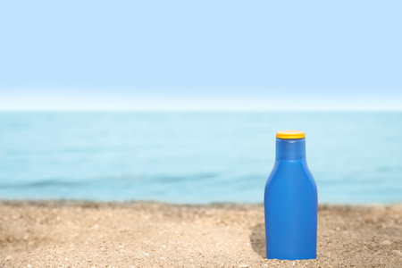 Bottle of sun protection body cream on beach, space for designの写真素材