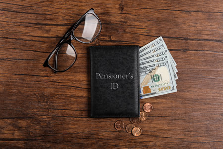 Pension certificate with American money and glasses on wooden table, flat layの写真素材