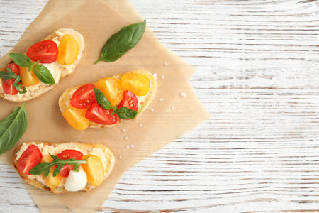 Delicious tomato bruschettas on white wooden background, top view. Space for textの写真素材