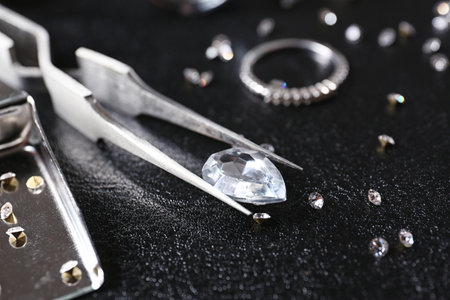 Jewels and tweezers on black leather surfaceの写真素材