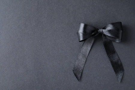 Black ribbon bow on dark background, top view with space for text. funeral symbolの写真素材