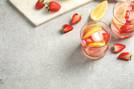 Tasty refreshing drink with strawberries and lemon on light gray table, above view. Space for textの写真素材