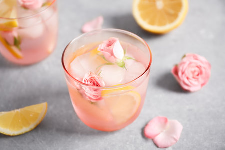 Tasty refreshing lemon drink with roses on light gray tableの写真素材