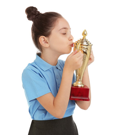 Happy girl in school uniform kissing golden winning cup isolated on whiteの写真素材
