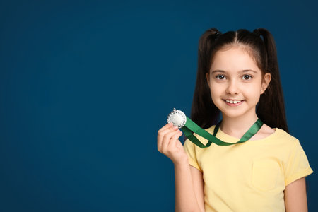 Happy girl with gold medal on dark blue background. Space for textの写真素材