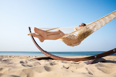 Young woman relaxing in hammock on the beachの写真素材