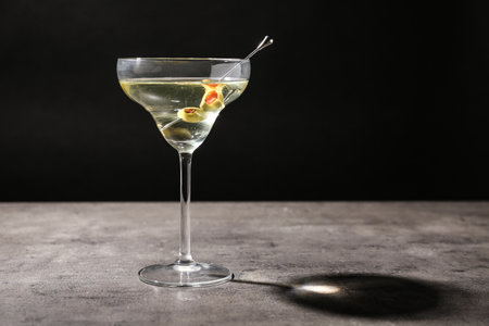 Glass of Classic Dry Martini with olives on gray table against black background. Space for textの写真素材