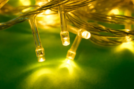Glowing Christmas lights on green background, closeupの写真素材