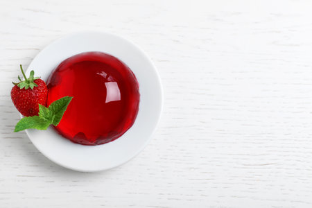 Delicious fresh red jelly with berries and mint on white wooden table, top view. Space for textの写真素材